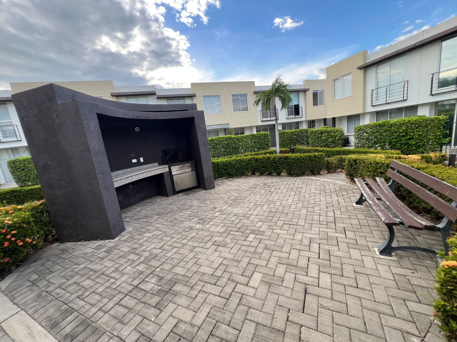 Zona BBQ exterior con bancas y jardines del conjunto